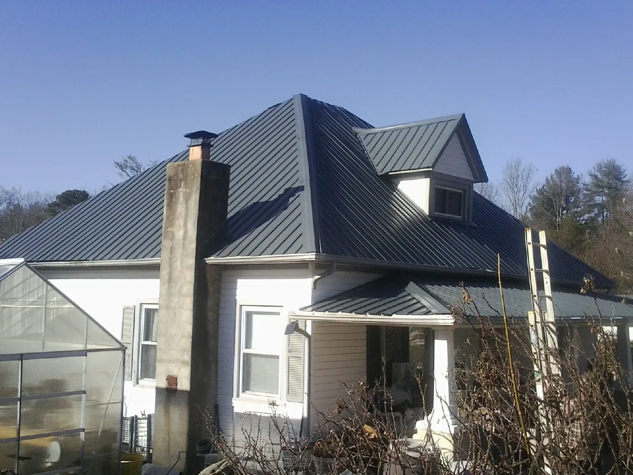 Dark blue standing seam metal roof on a white farmhouse with dormer — Slate & Tile Roof Repair by Roofing Brothers in Walhonding