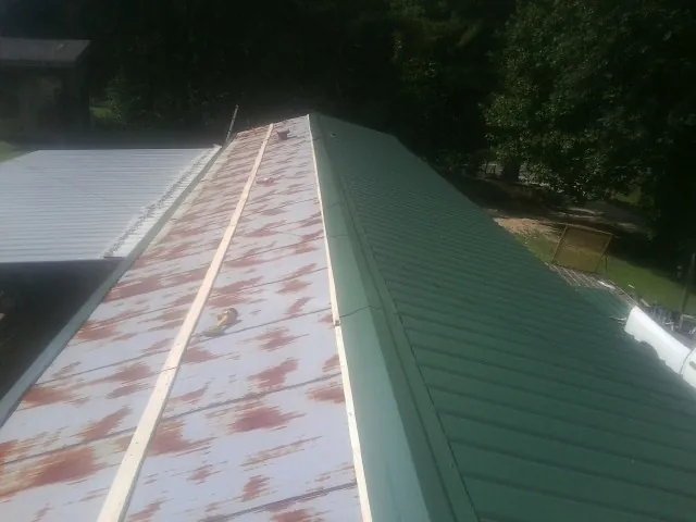 Old rusted panels beside newly installed green metal roofing — Wind Damage Roof Repair by Roofing Brothers in Walhonding