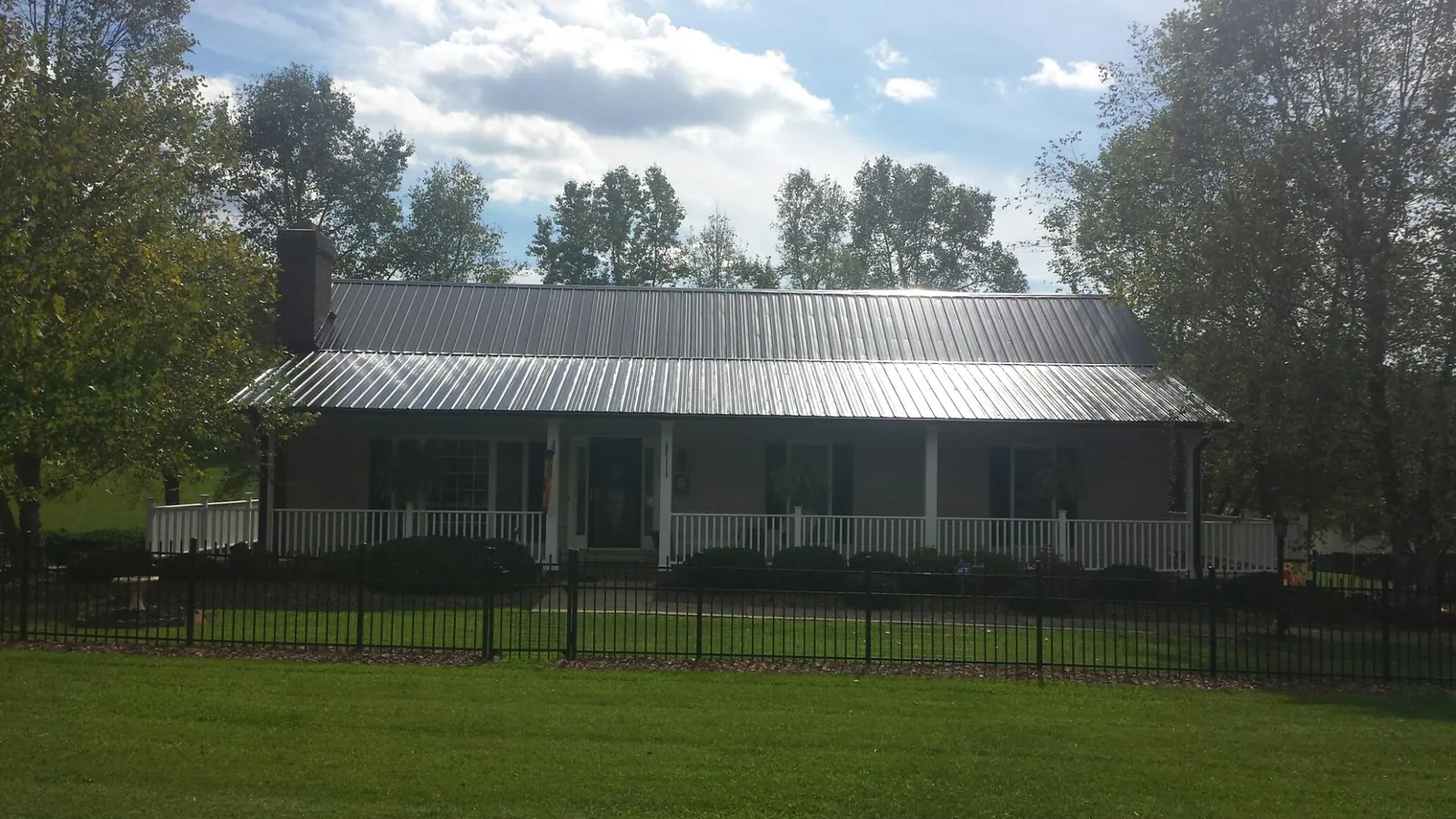 Gray metal roof on a brick ranch with a full width front porch — Gutter Guard Installation work by our crew in Walhonding