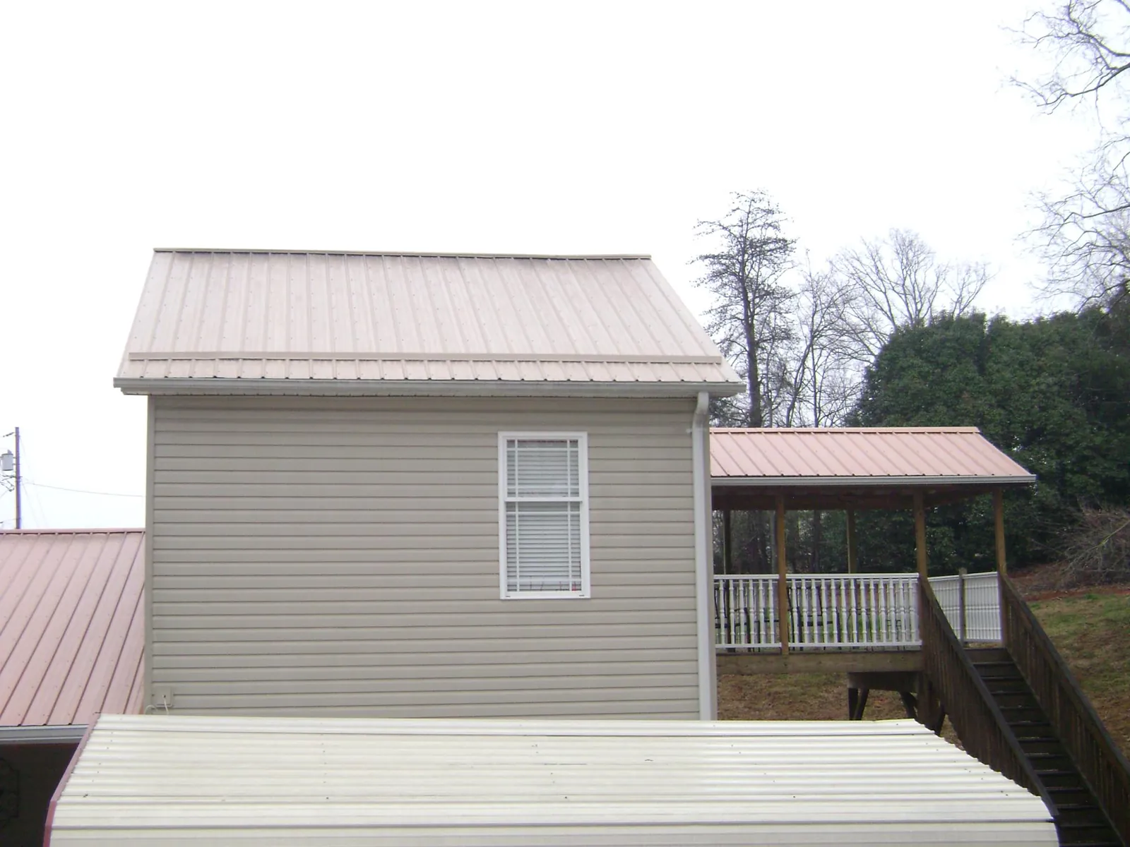 Tan metal roofs on a two story addition and attached porch, from a Roof Replacement job in Walhonding