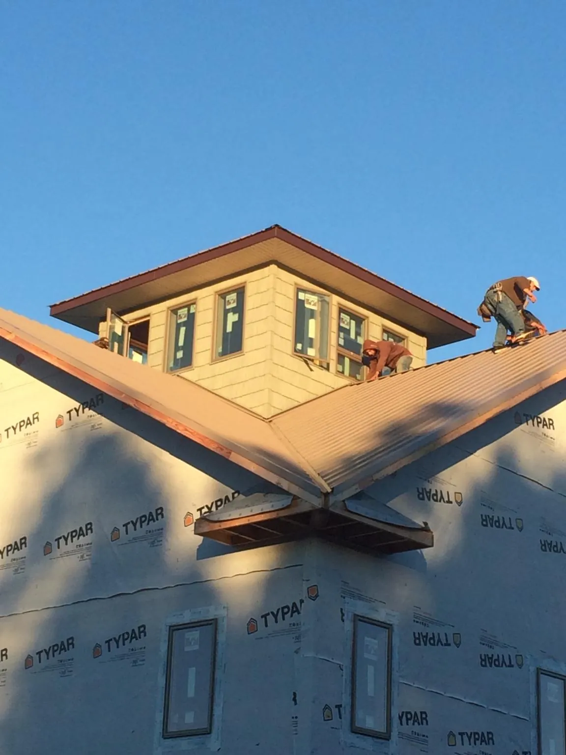 Roofers working around a rooftop cupola on a new metal roof at sunset — Roof Waterproofing in Walhonding by Roofing Brothers